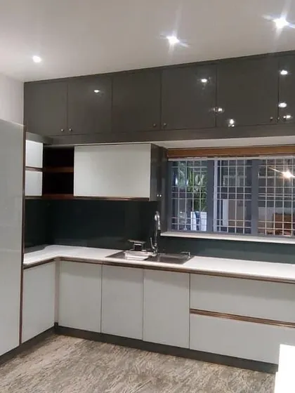 A two-tone kitchen with glossy dark grey upper cabinets and white lower cabinets. The large window allows for plenty of natural light, creating a balanced and modern cooking environment.