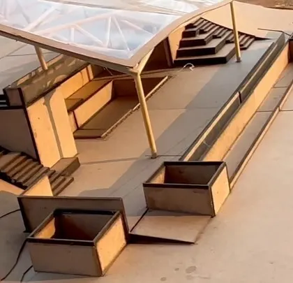 A close-up of the physical model for the yoga retreat's stage and pool area, showing the stepped seating and the lightweight roof structure.