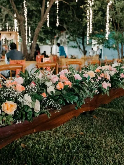 The long dining tables at the cocktail party are decorated with beautiful pastel floral runners, creating an elegant and romantic tablescape.