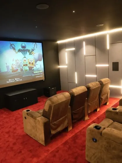 The view from the back row offers a perfect vantage point of the 150-inch Elite Screen. The combination of red, brown, and black creates a rich and inviting color scheme.