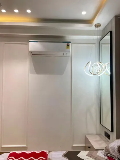 The wall opposite the bed features simple, clean paneling, maintaining the room's minimalist aesthetic. A modern, artistic pendant light adds a touch of flair.
