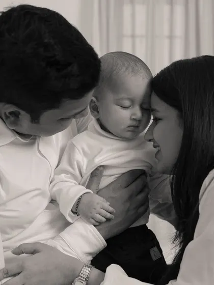 A tender black and white portrait capturing the quiet, loving bond between parents and their newborn.