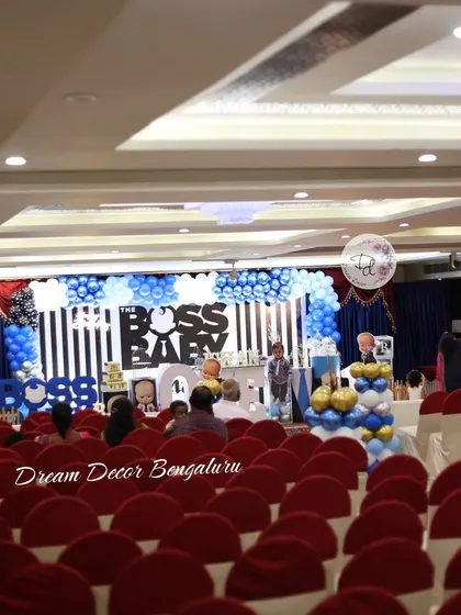 A wide shot of a Boss Baby themed party, showing how we can decorate a large hall. The stage is the main focus, with plenty of seating arranged for guests to enjoy the celebration.