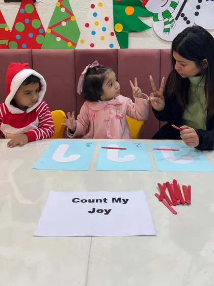 A moment of understanding as a teacher uses her fingers to reinforce the concept of "two." We use multiple methods to explain concepts, ensuring every child connects with the lesson.