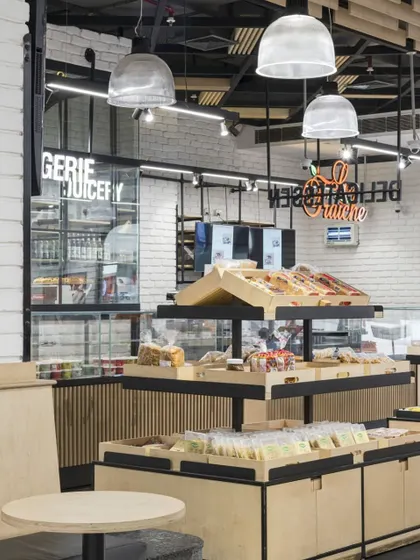 The bakery and juicery section at Le Marche features its own distinct identity within the larger store. The use of neon signage and dedicated display cases creates a lively 'shop-in-shop' feel, enhancing the customer experience.