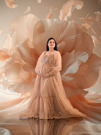 Soft, dreamy, and ethereal. The mom-to-be is surrounded by a cloud of flowing peach fabric and petals, wearing a matching sequined gown that exudes pure grace.