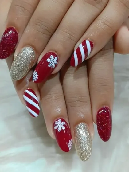 A festive Christmas-themed set with candy cane stripes, snowflake art, and full-coverage gold and red glitter nails.