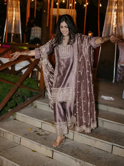A guest shows off her henna-adorned hands while making a graceful entrance at the Mehendi night.