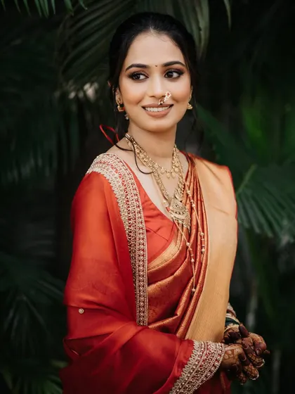 A beautiful, smiling portrait of the Maharashtrian bride in her traditional red and gold wedding saree.