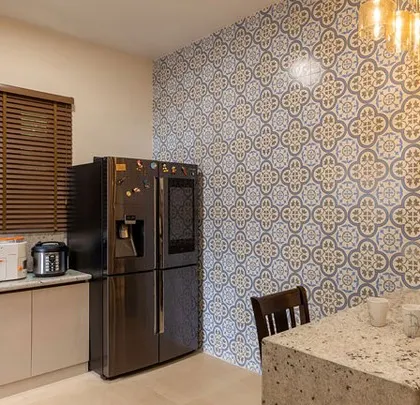 The utility side of the kitchen, featuring a large refrigerator and a wall with Moroccan-style tiles, adding a pop of pattern and color.
