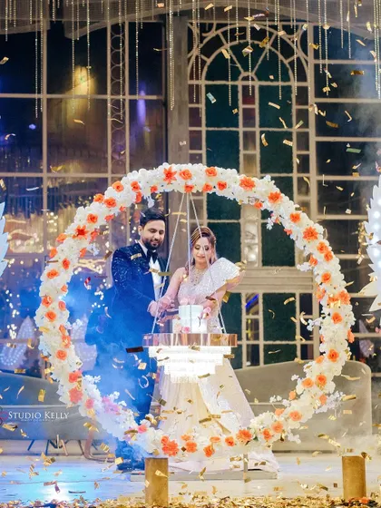 The couple cuts their cake, which is suspended in a beautiful floral ring, creating a unique and memorable reception moment.