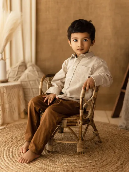 A serious and handsome portrait of a young boy in a boho-inspired setting. His direct gaze is captivating.