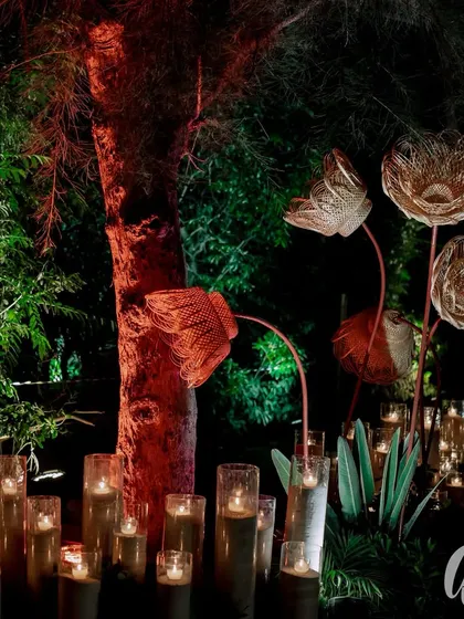 We love to integrate artistic, sculptural elements. These oversized, hand-woven flowers, illuminated by surrounding candles, added a touch of modern craft to the rustic, natural setting of the event entrance.