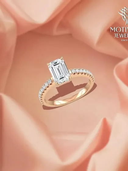 A classic emerald-cut diamond solitaire ring with a delicate diamond-paved band. This is a timeless design that exudes sophistication and understated luxury.