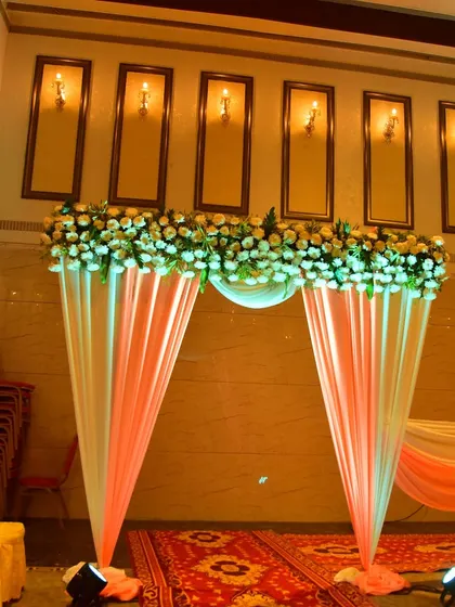A beautiful entrance arch with peach drapes and a white floral border, perfect for an elegant reception.