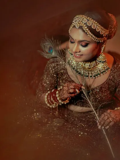 An artistic portrait of the bride with a peacock feather, adding a touch of traditional symbolism.