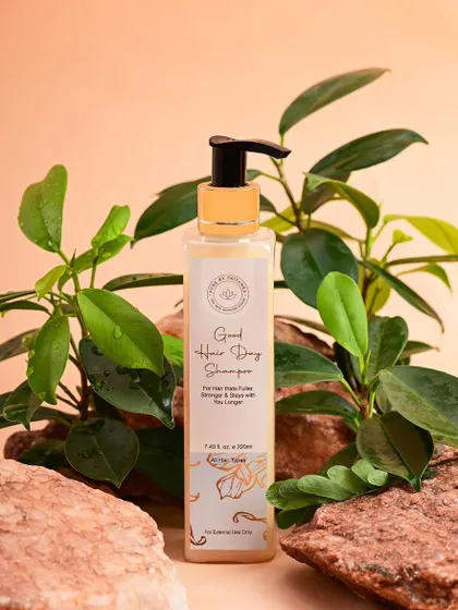A shot of Pure by Priyanka's "Good Hair Day" shampoo, styled with natural rocks and greenery. This setup reinforces the brand's connection to natural ingredients and effective hair care.
