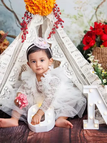 Exploring the light-up letters during her first birthday photoshoot. The warm lights add a magical glow to the photos.
