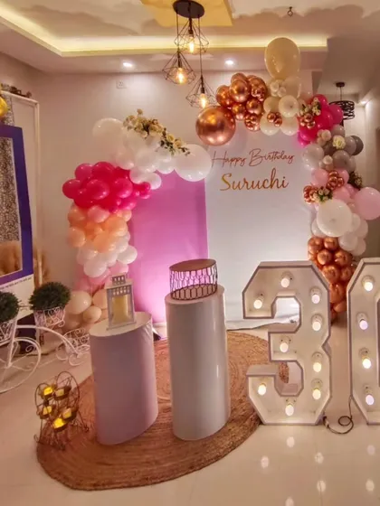 A stylish 30th birthday party setup for a home celebration. The rose gold and pink balloon arch and large marquee numbers instantly transform the space.