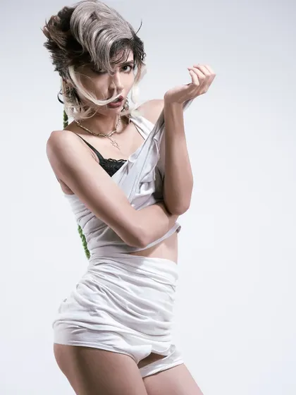 A playful, over-the-shoulder pose that contrasts with the edginess of the styling.