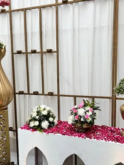 Another view of the traditional welcome table, with a bed of rose petals and elegant floral arrangements in golden vases.