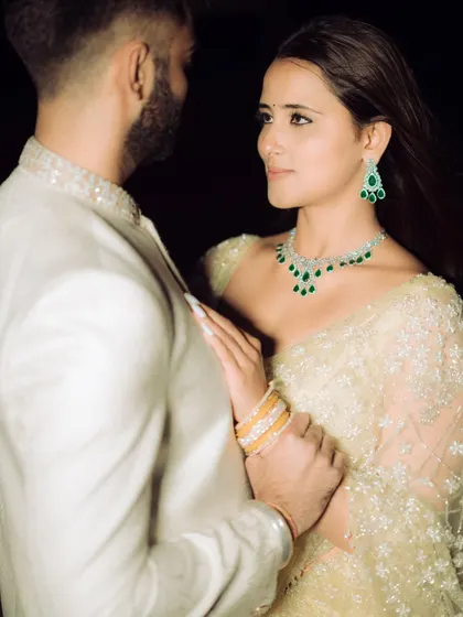 A cinematic and romantic portrait against a dark background. The dramatic lighting highlights the couple's features and the intimacy of the moment.