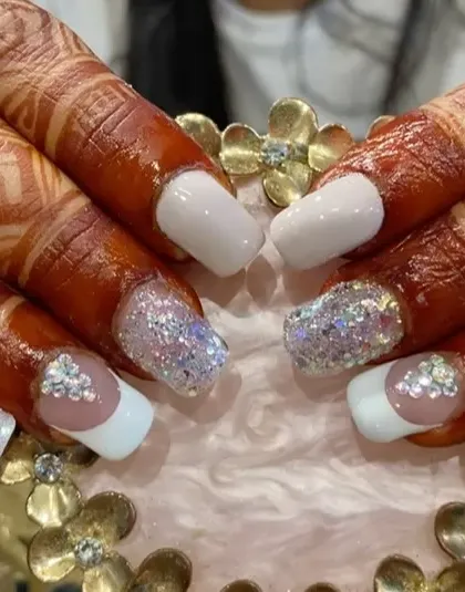 A closer look at bridal nails, showing the detailed crystal work on the accent nail against the intricate henna design.