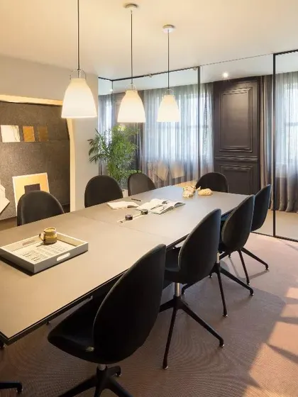 A sleek and modern meeting room with a dark color palette and minimalist furniture. The design uses sheer curtains to control light and privacy, creating a sophisticated and focused environment for important discussions.