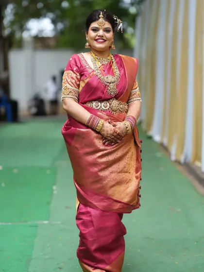 A full-length view showing how the traditional jewellery complements the entire bridal ensemble. The layered necklaces and vaddanam create a beautiful silhouette.