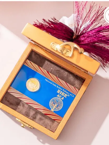 A wooden box with a decorative tassel, designed for presenting a gold or silver coin as a corporate or wedding gift.