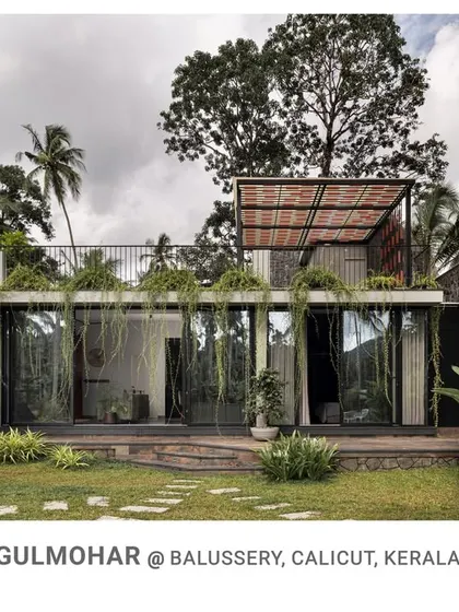 The front facade of Gulmohar, showing how floor-to-ceiling glass walls connect the interior living spaces directly to the garden, creating a seamless indoor-outdoor experience.