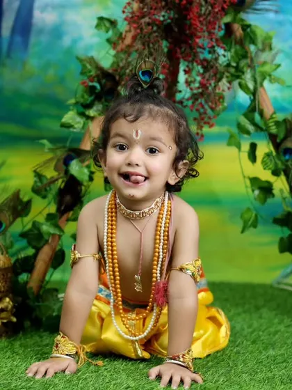 A cheeky and adorable expression that perfectly captures the playful spirit of Little Krishna. The vibrant colors of the set make this a joyful and memorable portrait.