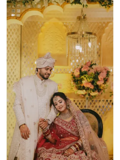 A classic portrait against a beautifully decorated stage. The bride rests her head on the groom's shoulder, a picture of comfort and love.