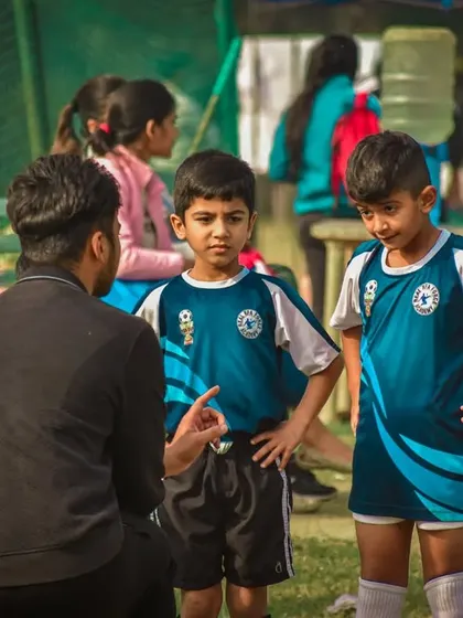 A coach giving tactical advice to his two young players during a break.