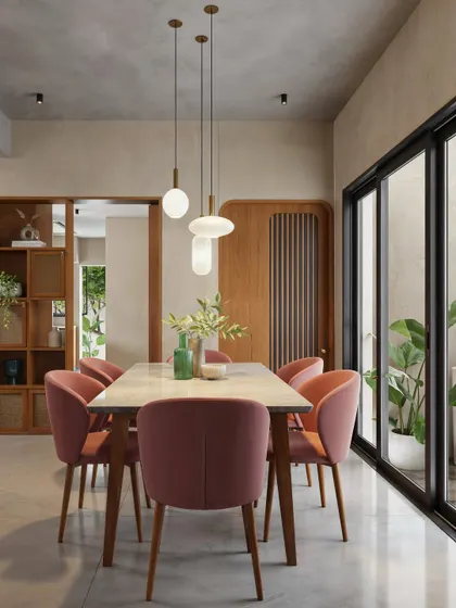 This dining area uses a warm, earthy color palette with dusty rose chairs and a wooden table. The space is lit by a cluster of modern pendant lights and opens onto a patio through large sliding doors.