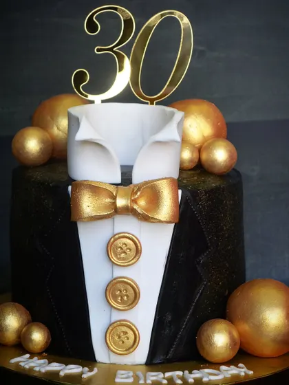 A sharp-looking tuxedo cake for a 30th birthday. The design features a crisp fondant shirt, bow tie, and jacket, perfect for a formal celebration.