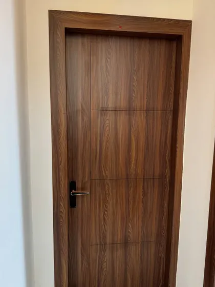 A simple yet elegant flush door with a dark wood laminate finish. The clean lines and modern black handle are perfect for a contemporary home.