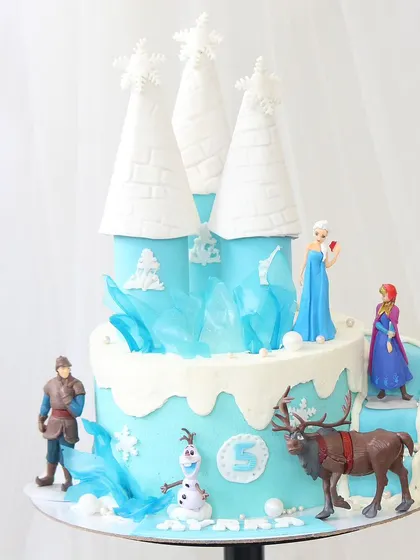 A magnificent "Frozen" castle cake perfect for a princess's fifth birthday. This design features a multi-level castle with icy blue details, sugar ice shards, and all the beloved characters from the movie.