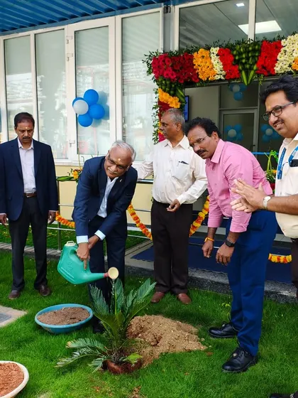 Another view of the watering ceremony, with smiles all around, celebrating the successful partnership and the new green addition to their campus.