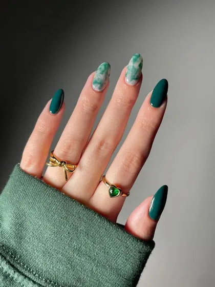 An elegant and sophisticated set featuring deep forest green paired with a realistic green marble accent nail on a chic almond shape.