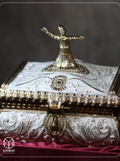 A close-up of the Sufi-inspired Rajwada Chest, showing the ornate white and gold-finished metalwork topped with a silvered whirling dervish. This is craftsmanship designed to honor a rich heritage.