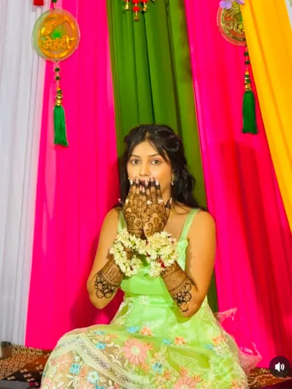 A fun and playful pose! This bride shows off her detailed palm designs during her vibrant mehndi ceremony.