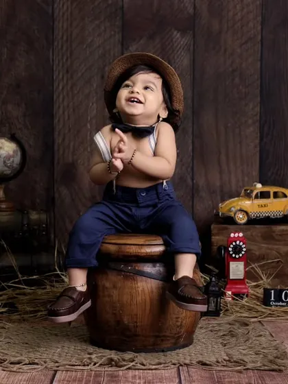A playful pose from our little vintage explorer. We encourage kids to interact with the props to capture their curiosity and personality during the photoshoot.