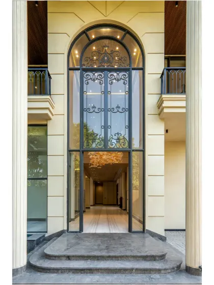 The grand arched entrance of the Sultanpur farmhouse, featuring intricate wrought iron detailing. This entrance is designed to create a lasting impression, blending classic elegance with modern aesthetics and flooding the interior with light.