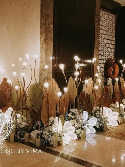 A classic and elegant reception setup symbolizing everlasting love. The stage features a modern, minimalist backdrop with custom monograms, floral arrangements, and soft lighting.