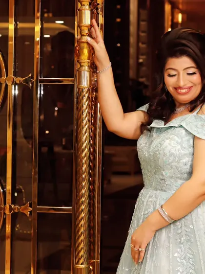 A portrait of the bride-to-be at her engagement party, smiling as she poses by an ornate golden door.