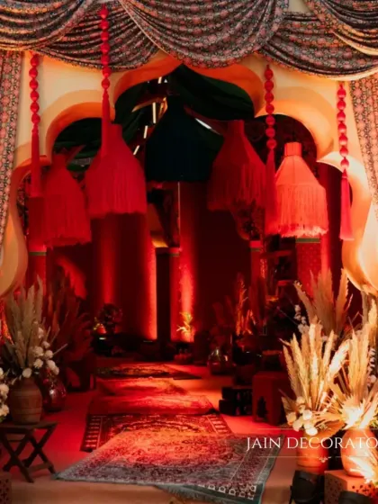 A grand entrance designed with rich textures and dramatic lighting. The red drapes and pampas grass arrangements create a luxurious and theatrical welcome for guests.