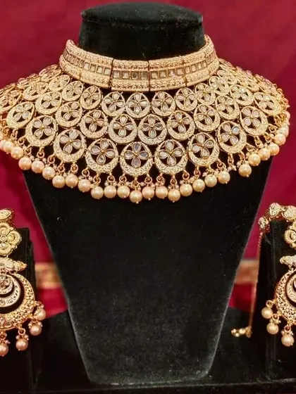 A classic gold-plated Polki choker set with matching chandbali earrings. The pearl drops add a touch of elegance to this timeless design.