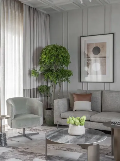 A serene corner of the Skyward Residence living room. The coffered ceiling and wall paneling add architectural interest, while the soft, curved furniture invites you to sit and relax.