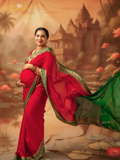 The flowing pallu of the saree adds a beautiful sense of movement to this portrait. The mom-to-be looks absolutely radiant against the painted temple backdrop.
